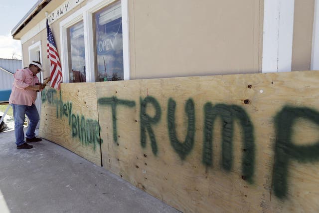A Houston man attaches a sign reading ‘Bet They Blame Trump’ at his business damaged in the wake of Harvey