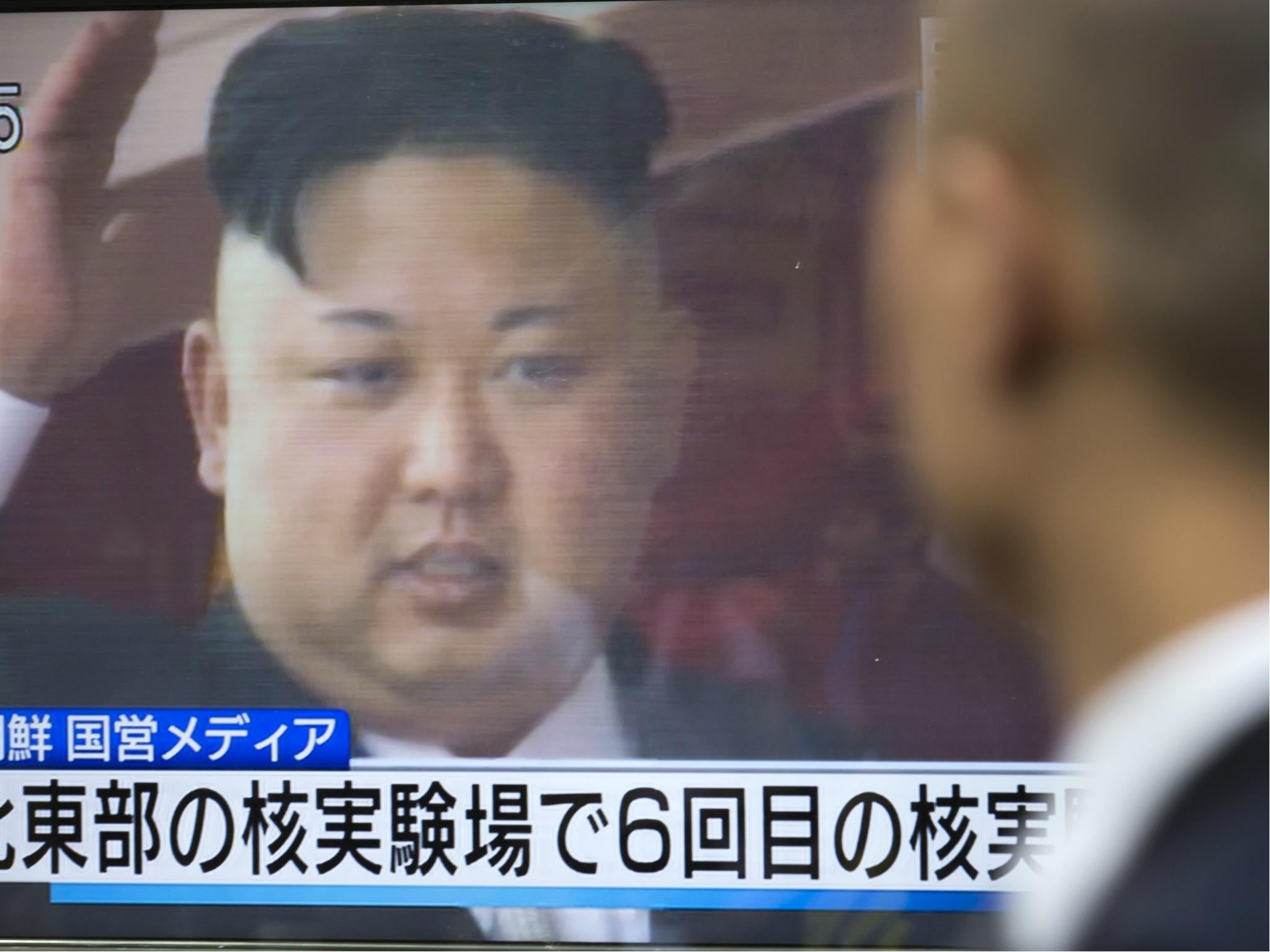 A pedestrian watches a monitor showing an image of North Korean leader Kim Jong-Un in a news program reporting on North Korea's 6th nuclear test on 3 September 2017.