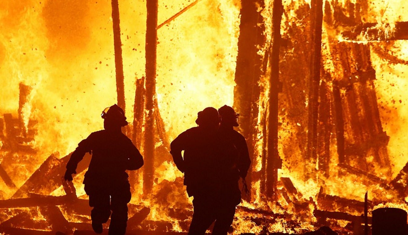 Firefighters run towards the burning effigy to try and save the man from the fire