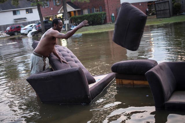 Vince Ware moves his sofas onto the sidewalk after his house was flooded by Tropical Storm Harvey in Houston, Texas