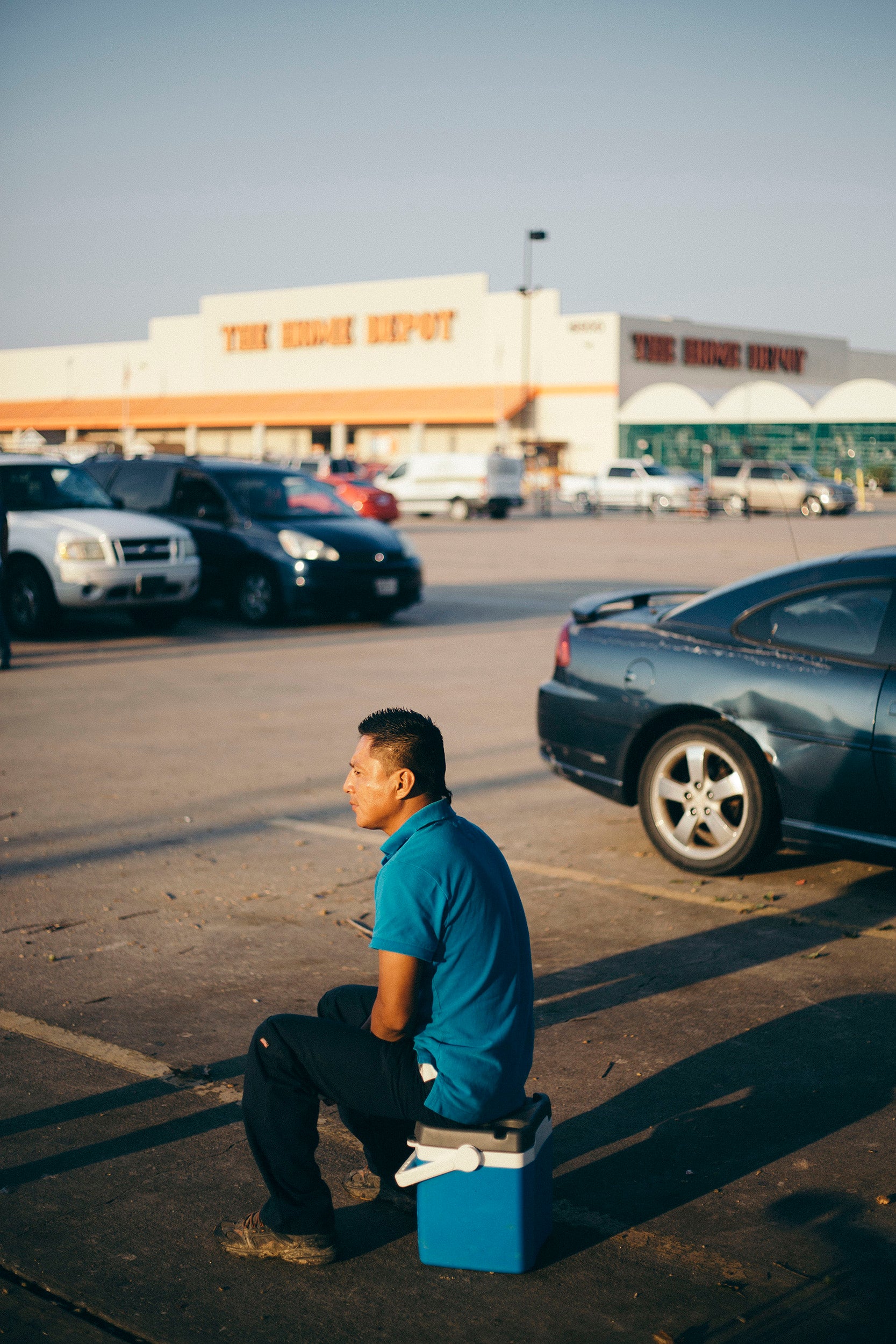 Samuel Enríquez, 36, is a day labourer. He sits on his lunch cooler waiting for work at the Home Depot in southwest Houston