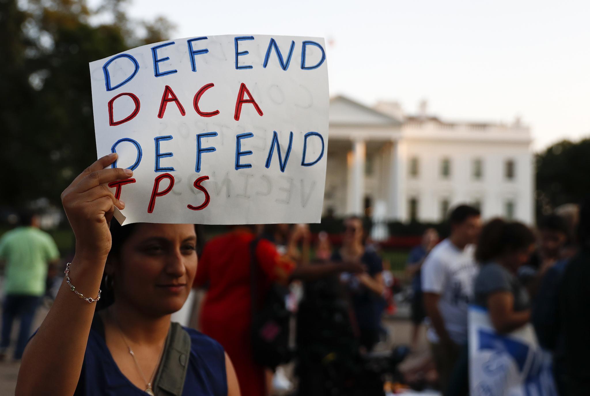 A woman holds up a sign that reads "Defend DACA Defend TPS" during a rally supporting Deferred Action for Childhood Arrivals, or DACA, outside the White House