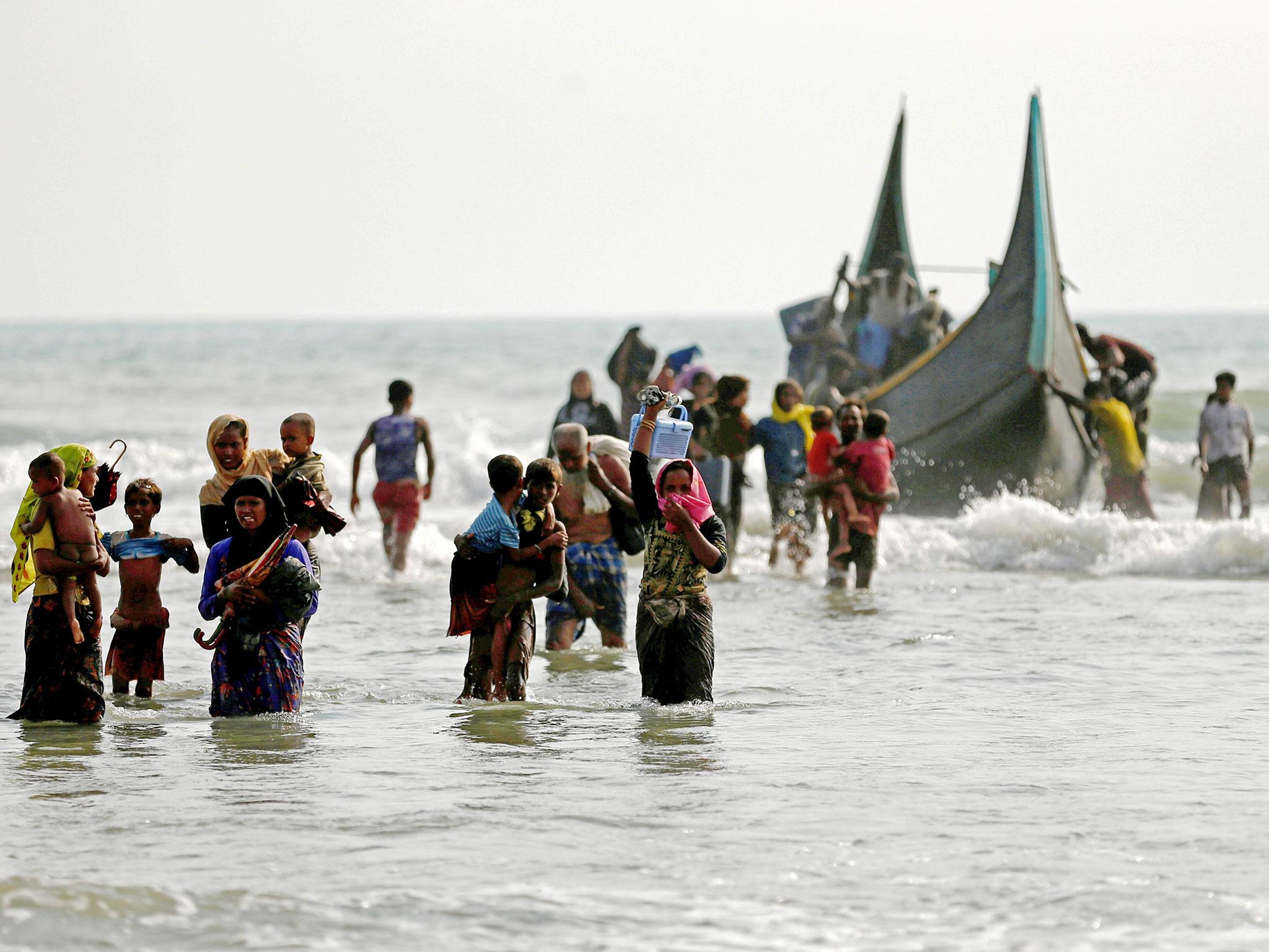 Rohingya refugees walk to the shore after crossing the Bangladesh-Myanmar border by boat through the Bay of Bengal in Teknaf, Bangladesh