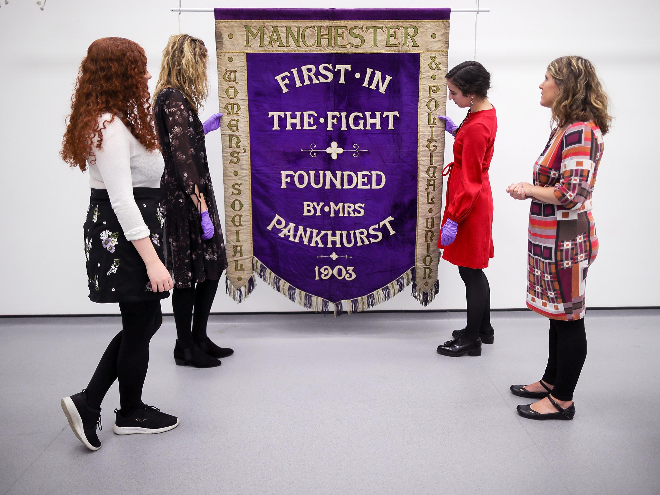 Conservators and museum staff pose as they inspect the Manchester suffragette banner hanging in the conservation department of Manchester People's History Museum. For nearly 50 years the banner lay undiscovered in a Leeds charity shop