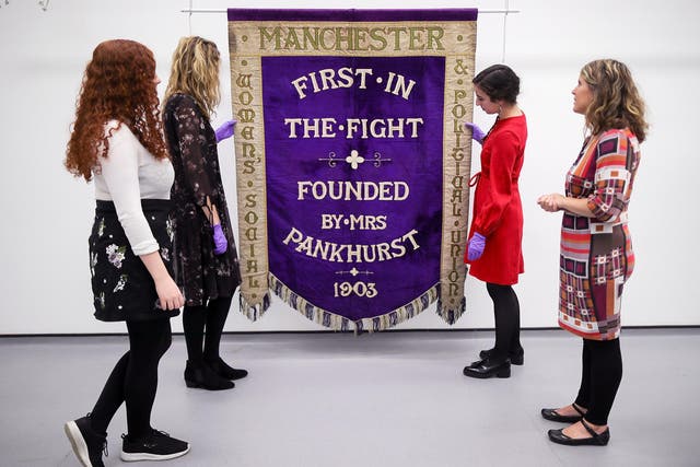 Conservators and museum staff pose as they inspect the Manchester suffragette banner hanging in the conservation department of Manchester People's History Museum. For nearly 50 years the banner lay undiscovered in a Leeds charity shop
