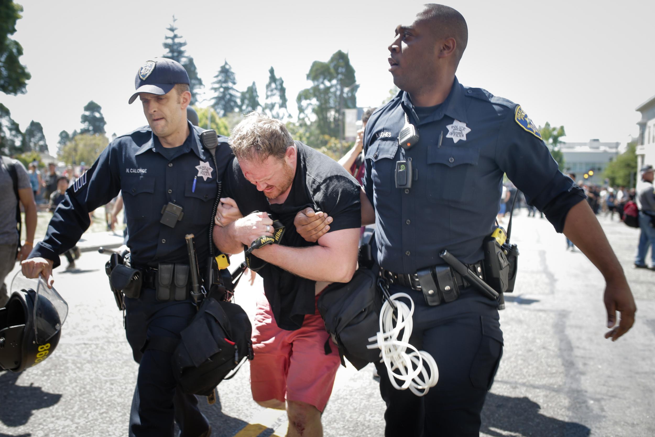 Police officers extricate a man who was beaten by people aligned with Antifa after he was suspected of being a right-wing Trump supporter (Getty)