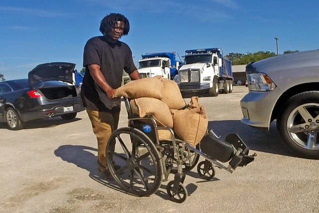 Tyrone Tomlinson, 27, of Orlando, uses a family wheelchair to ferry sandbags to be used on the front porch of their family home