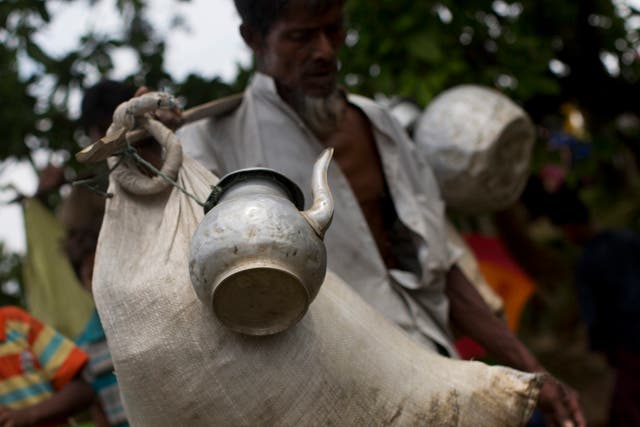 A Rohingya Muslim man arrives with a sack of belongings and a kettle tied to a stick