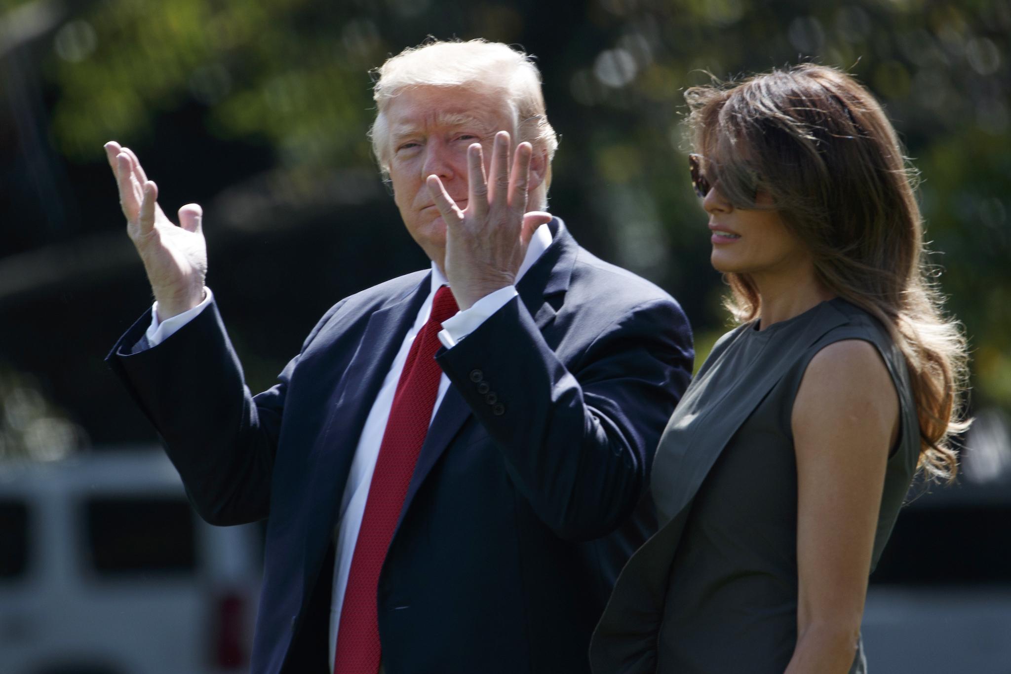 President Donald Trump gestures toward reporters as he walks with first lady Melania Trump to board Marine One