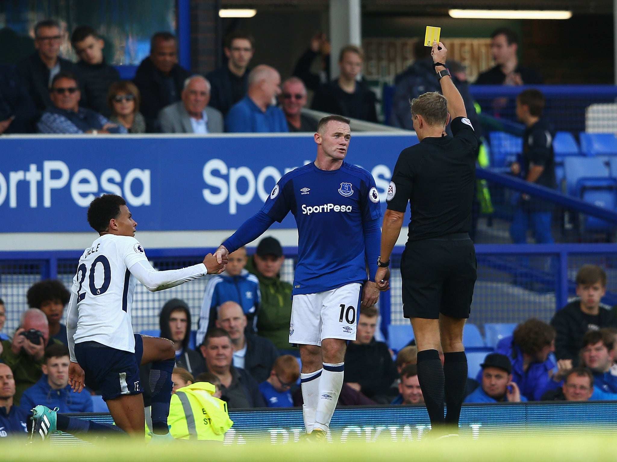 Wayne Rooney is shown a yellow card for his challenge on Alli