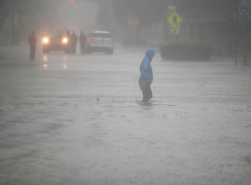 A person walks through a flooded street in the Brickell area of downtown Miami