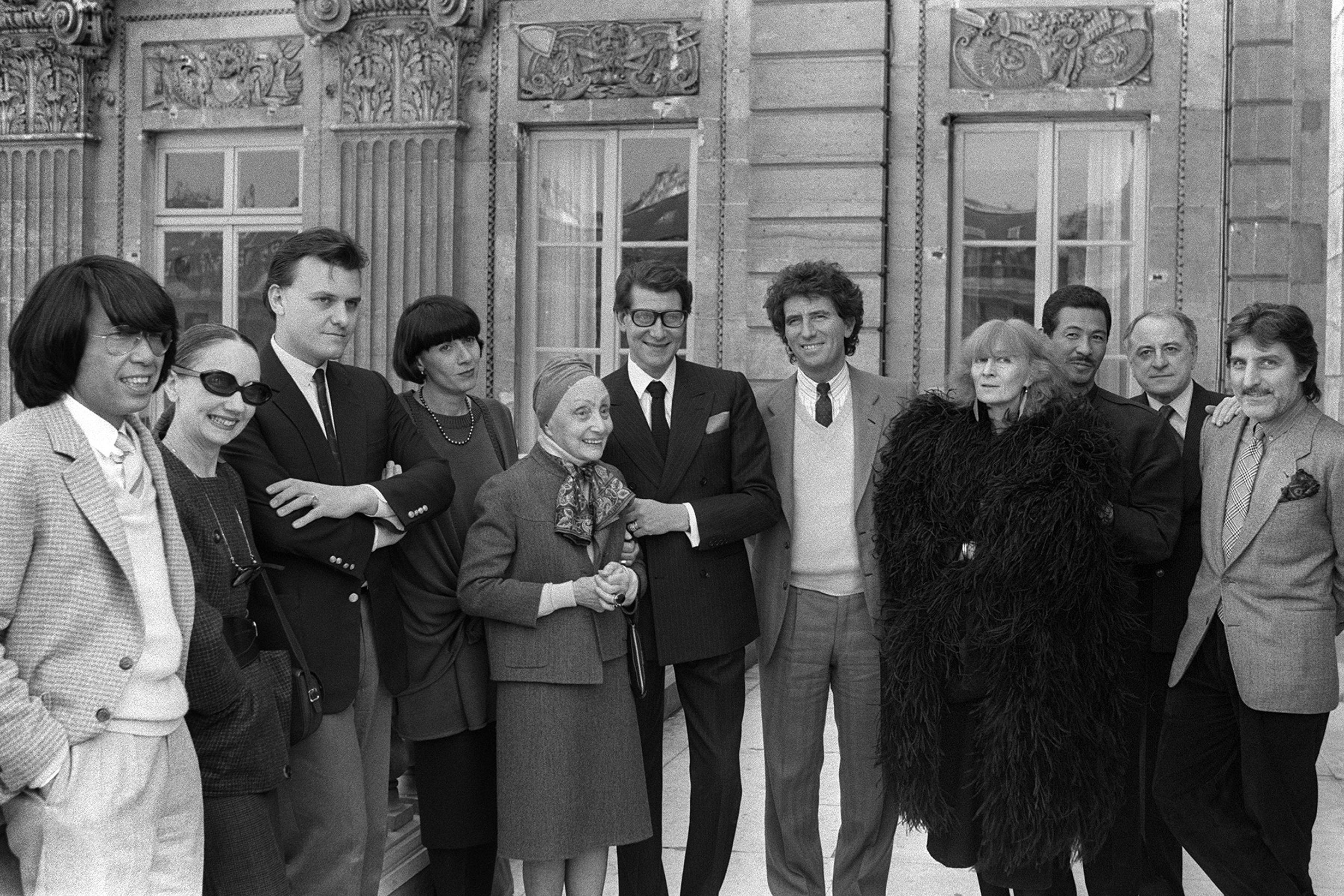 Pierre Bergé (second from right) and Yyves Saint Laurent (centre in dark suit) with other designers before Paris’s autumn/winter show in 1984