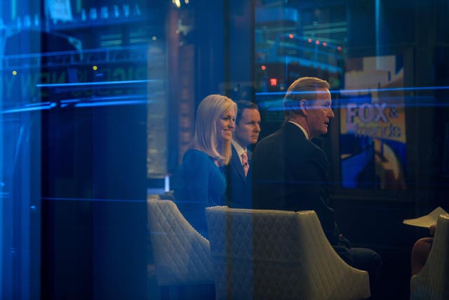 Seen through a window, hosts Brian Kilmeade, Ainsley Earhardt, and Steve Doocy broadcast 'Fox And Friends' from the Fox News studios