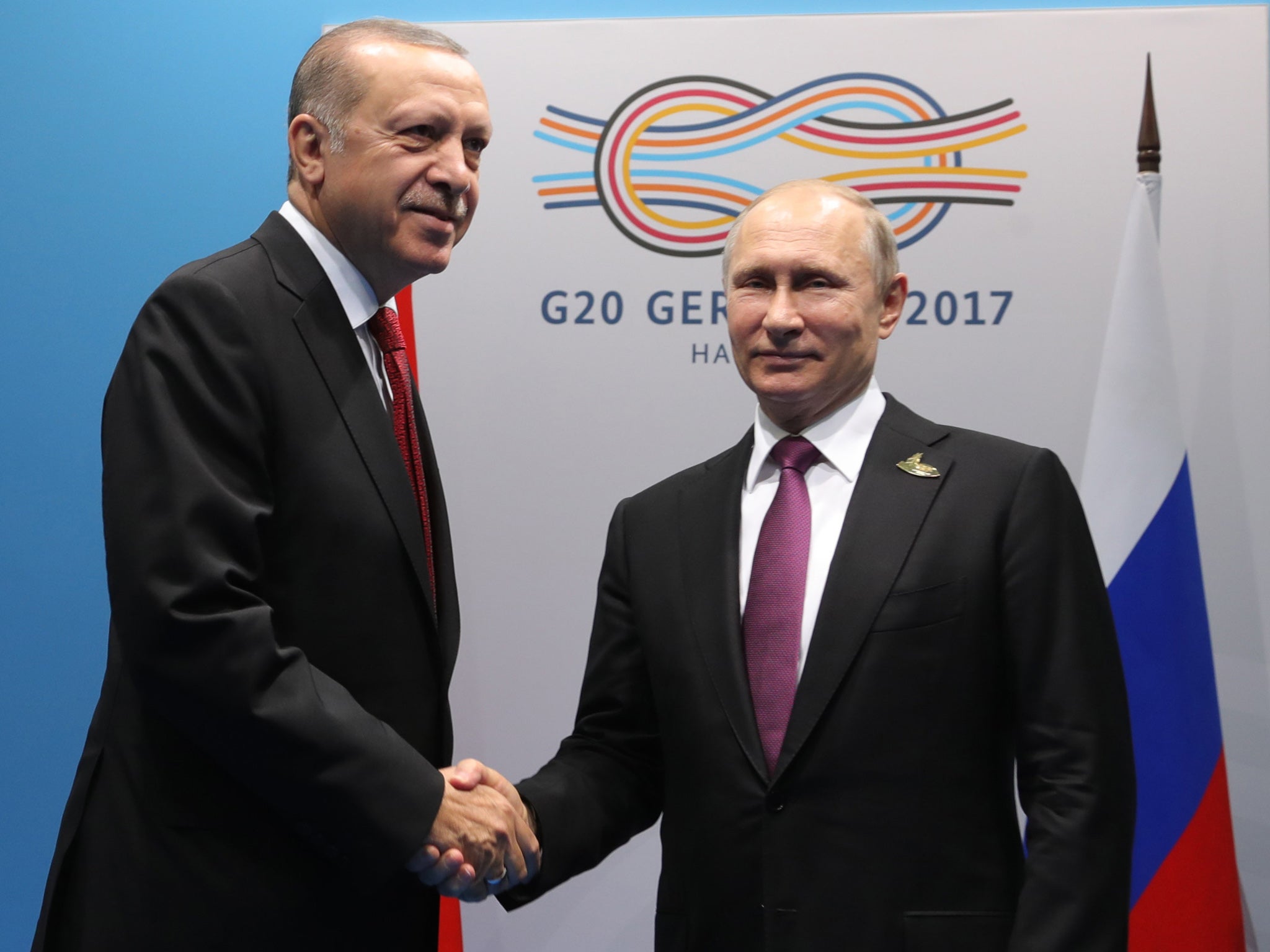 Recep Tayyip Erdogan and Vladimir Putin shake hands at the G20 summit in Germany in July. The pair have grown closer after being criticised by the West