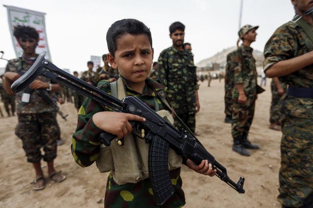 A boy poses with a Kalashnikov assault rifle during a gathering of newly-recruited Houthi fighters in the Yemeni capital of Sanaa on 16 July 16, 2017
