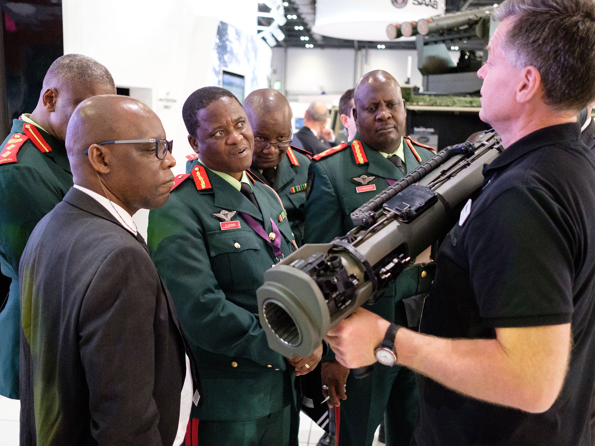 A group from the Botswana military watch as a member of the SAAB team explains their latest rocket-propelled weapons at the DSEI arms fair on 12 September