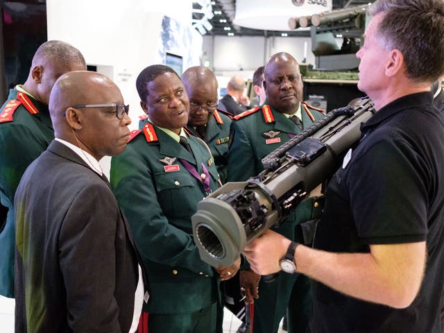 A group from the Botswana military watch as a member of the SAAB team explains their latest rocket-propelled weapons at the DSEI arms fair on 12 September