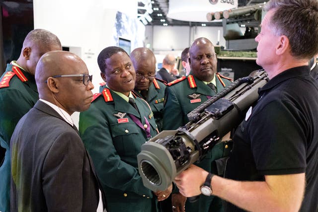 A group from the Botswana military watch as a member of the SAAB team explains their latest rocket-propelled weapons at the DSEI arms fair on 12 September