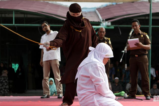 An Acehnese woman is whipped as punishment in front of the public in Banda Aceh, Indonesia