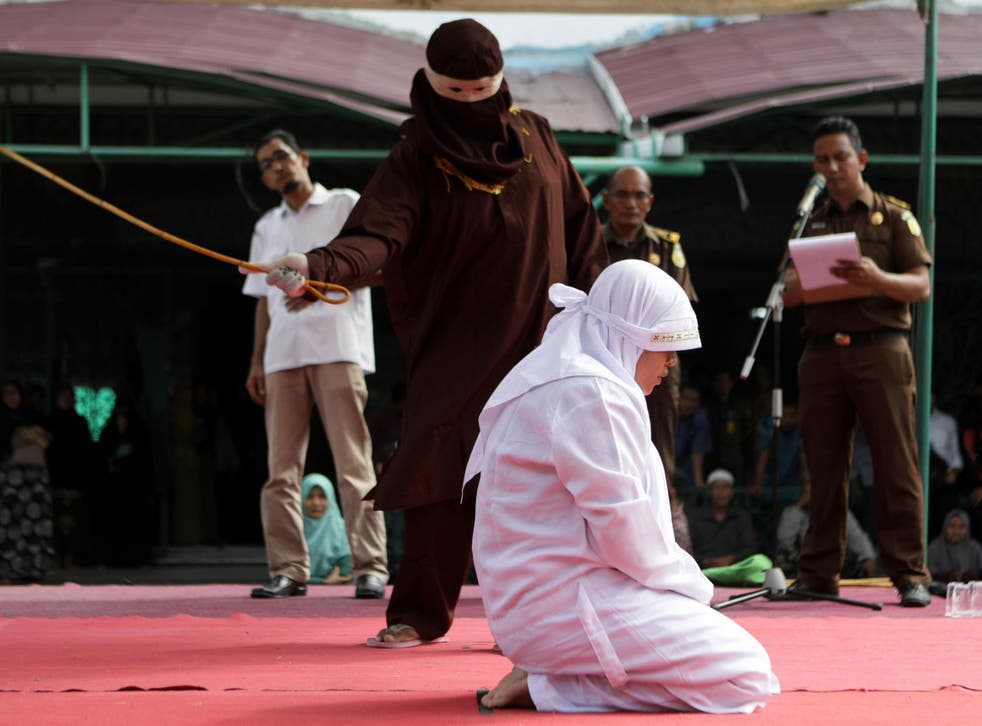 An Acehnese woman is whipped as punishment in front of the public in Banda Aceh, Indonesia