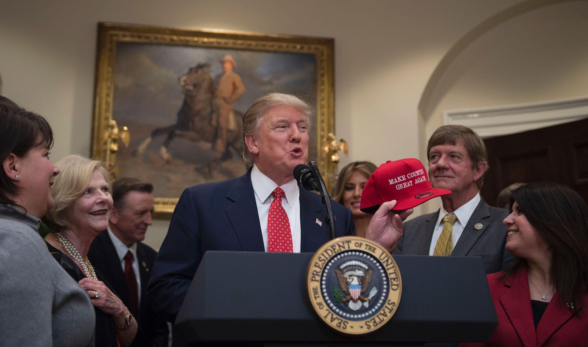 US President Donald Trump holds up a red cap that reads "Make Counties Great Again"