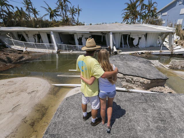 A man hugs his daughter while looking at the destruction after Hurricane Irma struck the Florida Keys in Islamorada, Florida