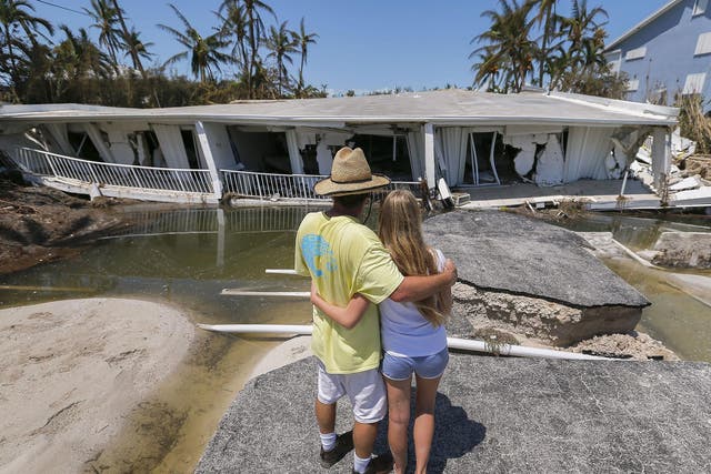 A man hugs his daughter while looking at the destruction after Hurricane Irma struck the Florida Keys in Islamorada, Florida