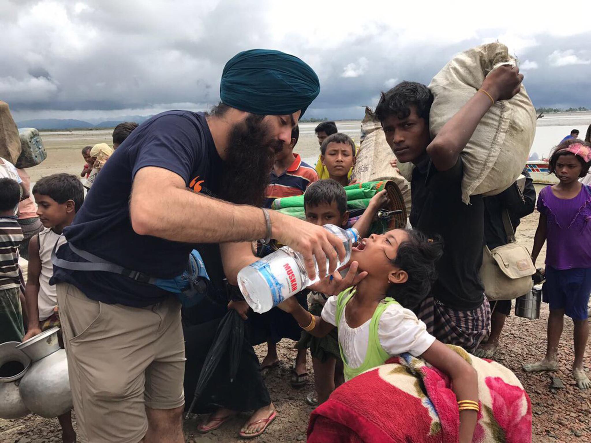 A volunteer gives water to a child said to be fleeing violence in Burma