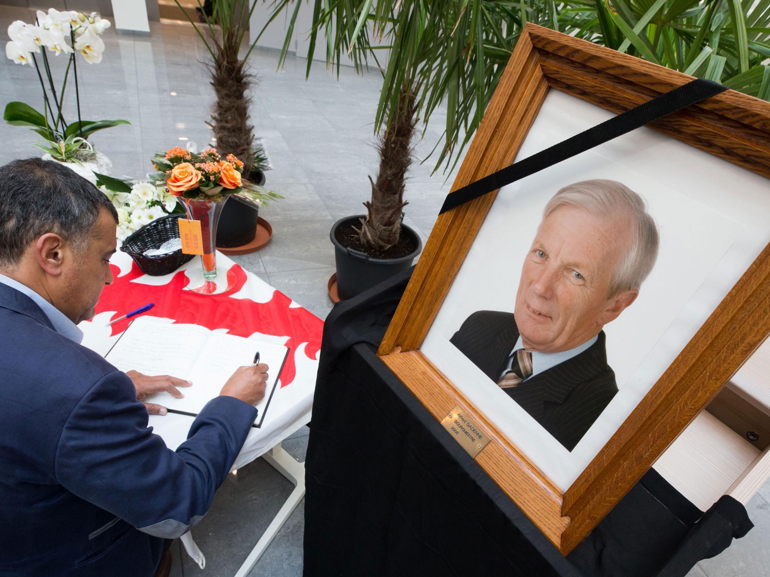 A man writes in the condolence book in Mouscron administrative centre, next to a portrait of Alfred Gadenne