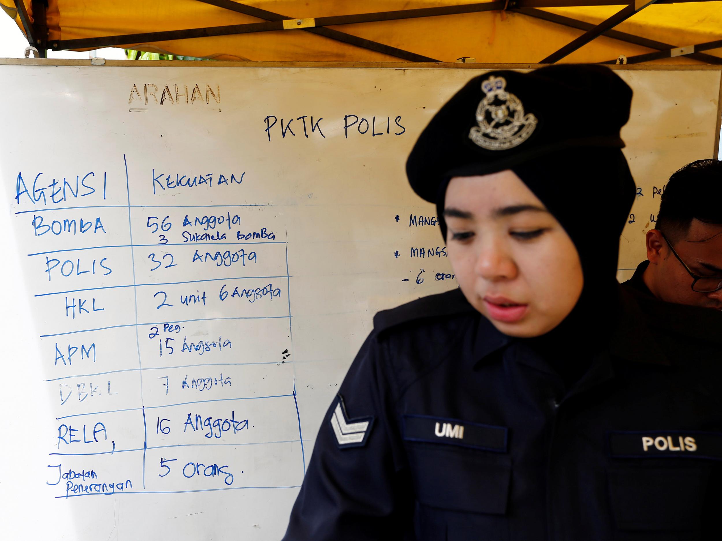 A policewoman stands next to a noticeboard accounting for manpower involved in the aftermath of the fire