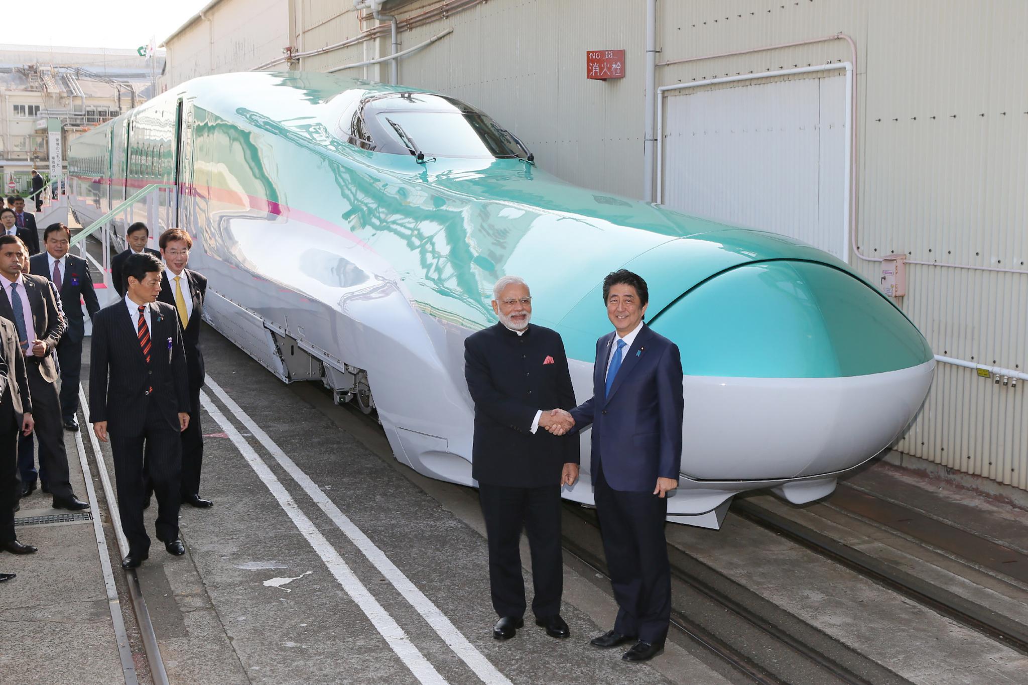 India's Prime Minister Narendra Modi (2nd R) and his Japanese counterpart Shinzo Abe (R) shake hands in front of a shinkansen train during their inspection at a bullet train manufacturing plant in Kobe, Hyogo prefecture on November 12, 2016