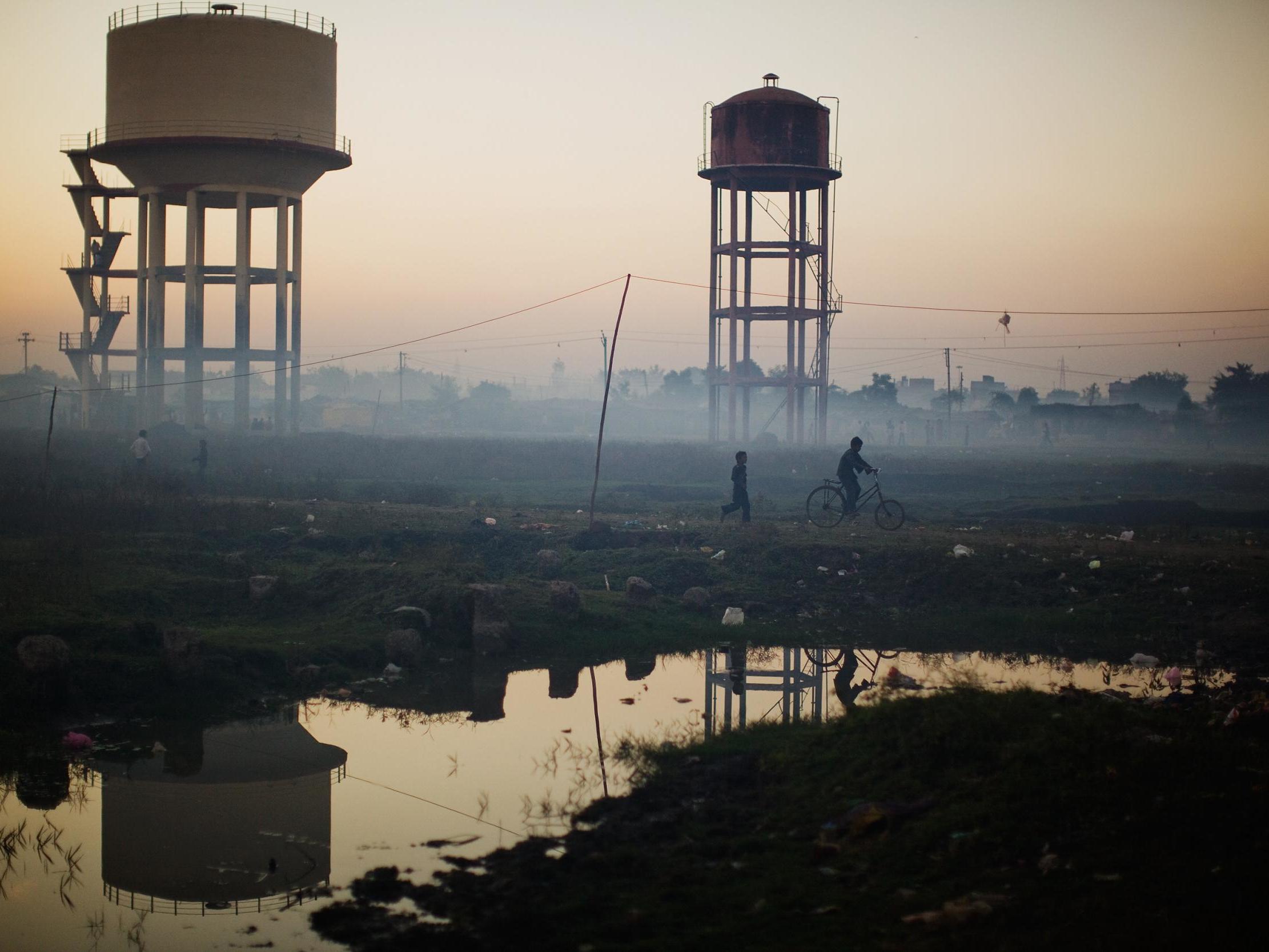Children play near water towers in front of their homes near the Union Carbide factory in Bhopal, India