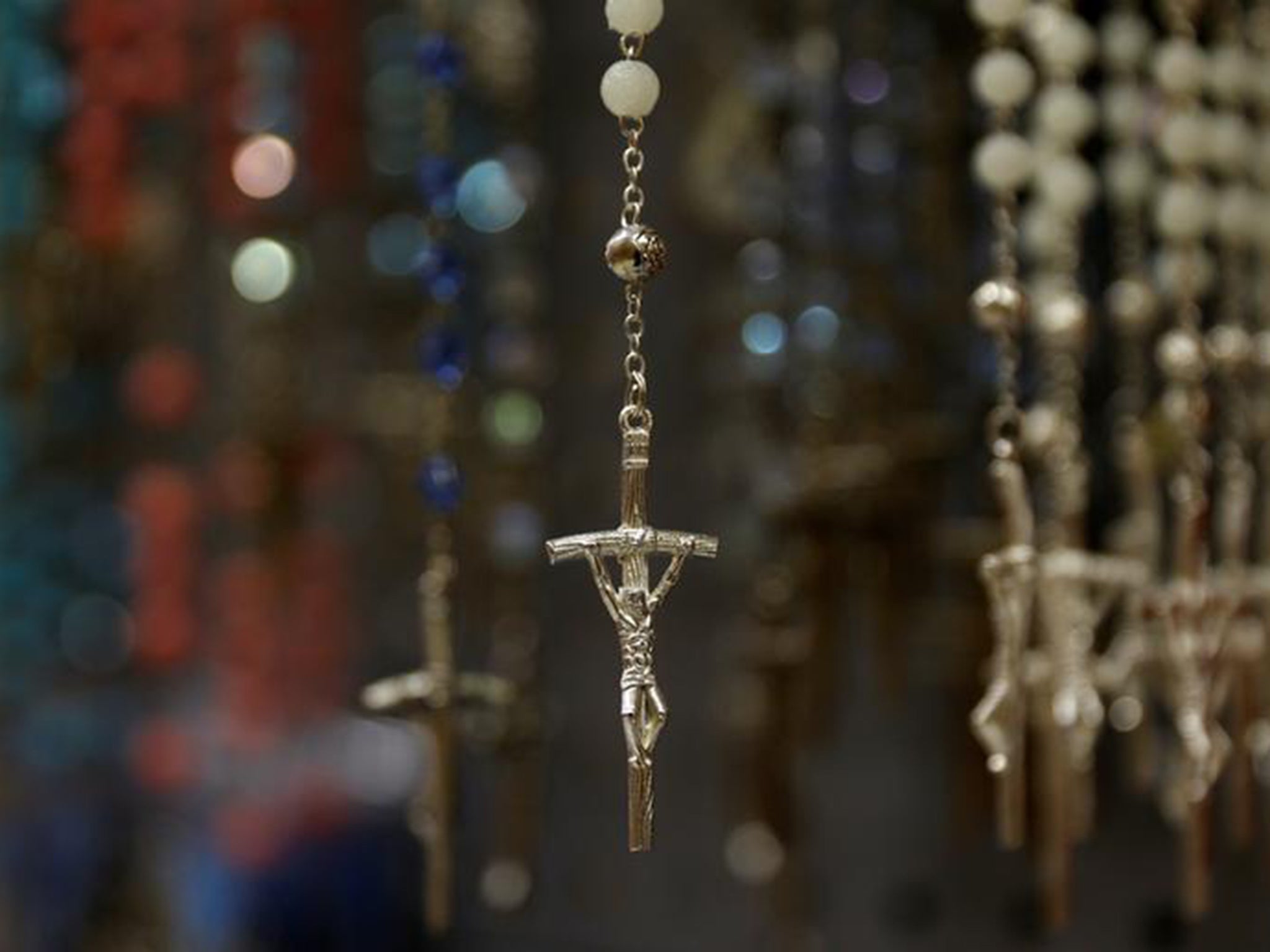 Crosses hang on the end of rosary beads displayed in a shop
