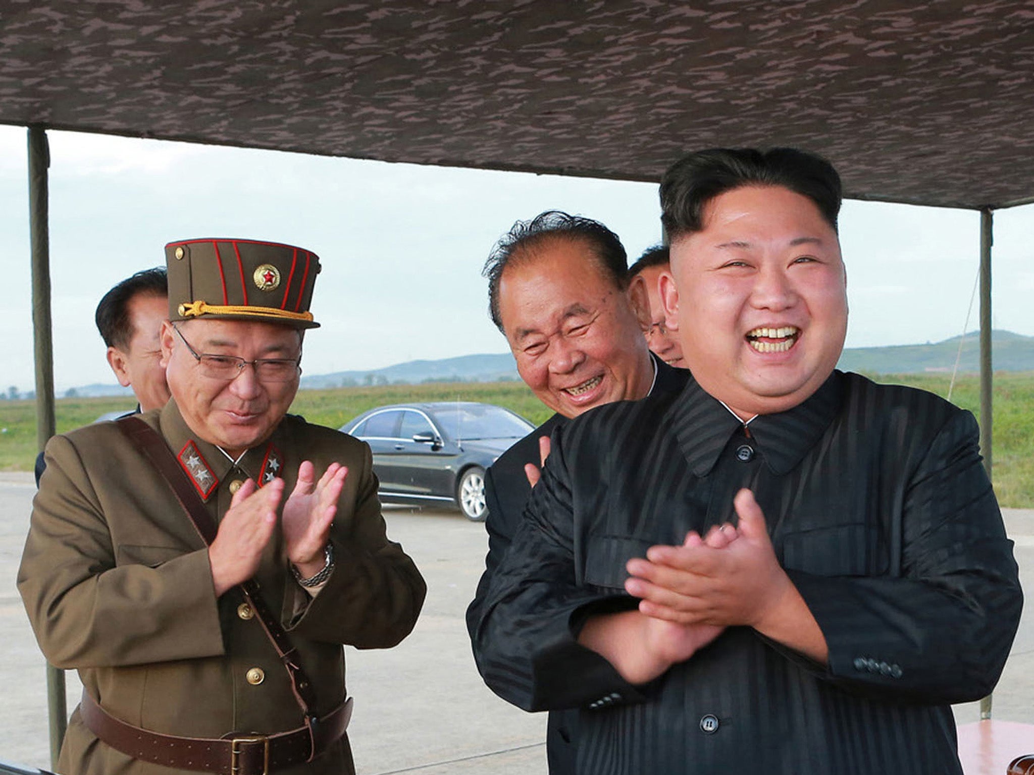 North Korean leader Kim Jong-un celebrates what was said to be the test launch of an intermediate range Hwasong-12 missile