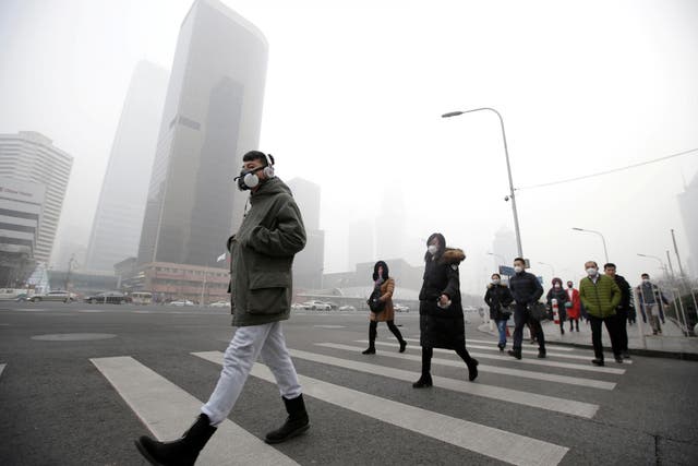People wear respiratory protection mask walks toward an office amid heavy air pollution in Beijing's central business district