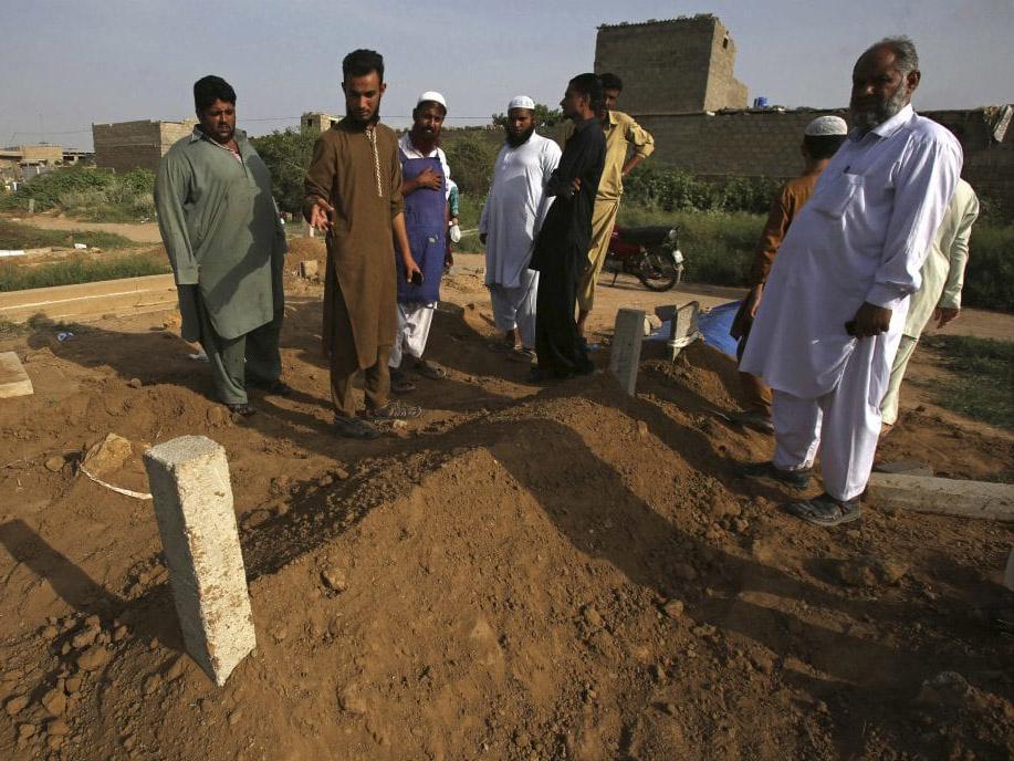 People look at the graves of victims of two alleged “honour” killings, in Karachi, Pakistan, on Wednesday