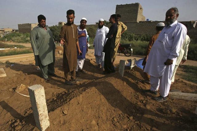 People look at the graves of victims of two alleged “honour” killings, in Karachi, Pakistan, on Wednesday