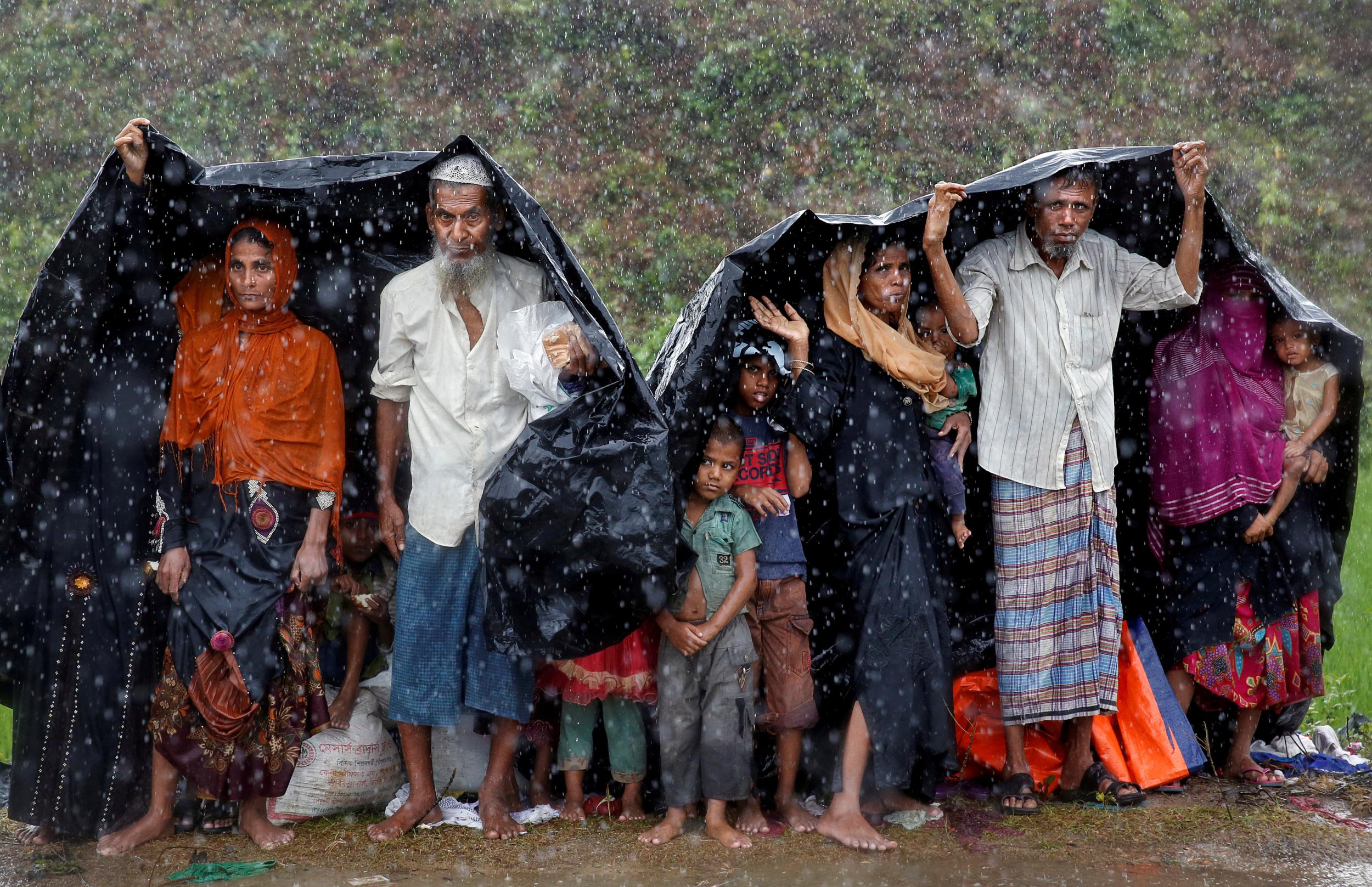 Rohingya refugees shelter from the rain in at a camp in Cox's Bazar, Bangladesh