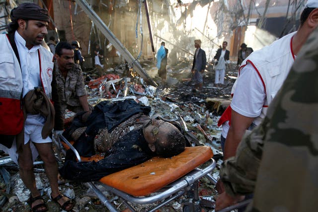 Yemeni rescue workers carry a victim on a stretcher amid the rubble of a destroyed funeral hall building following reported airstrikes by Saudi-led coalition air-planes on the capital Sanaa