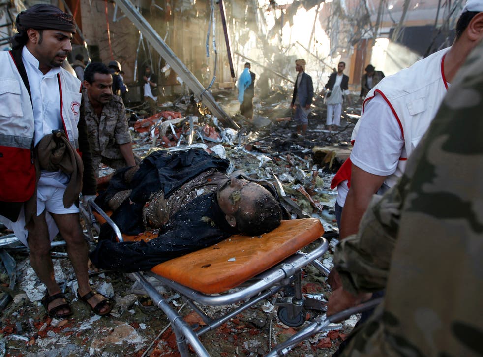 Yemeni rescue workers carry a victim on a stretcher amid the rubble of a destroyed funeral hall building following reported airstrikes by Saudi-led coalition air-planes on the capital Sanaa