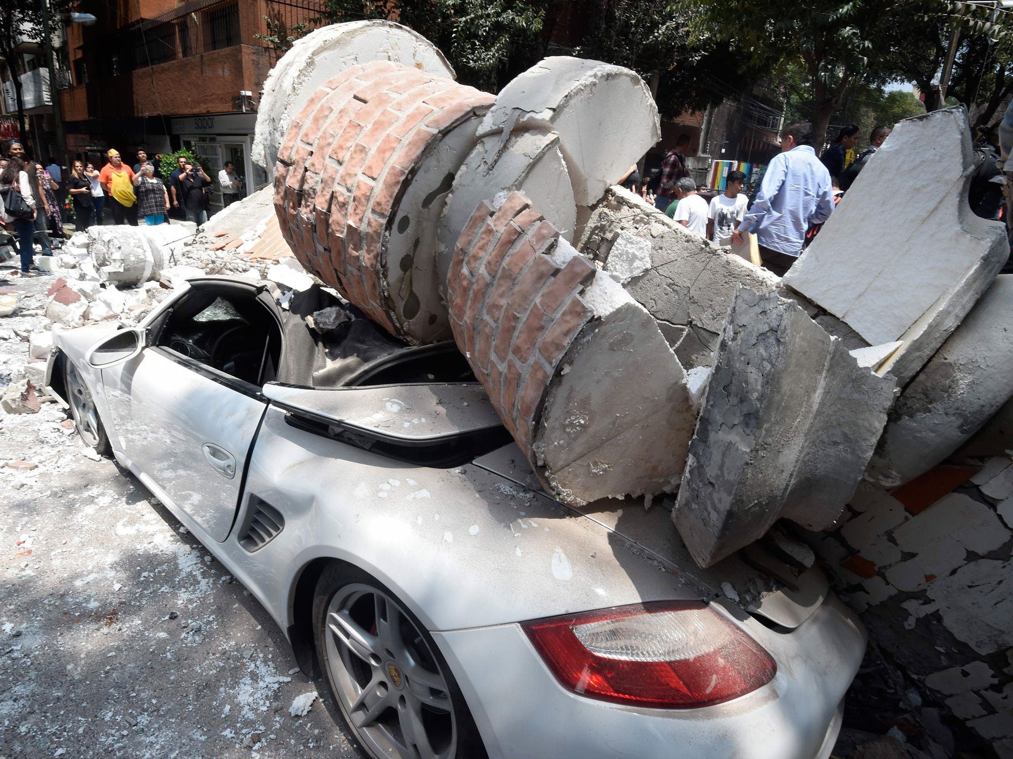 A car crashed by debris from a damaged building after a quake rattled Mexico City