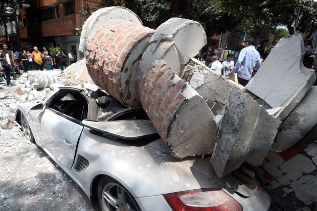 A car crashed by debris from a damaged building after a quake rattled Mexico City