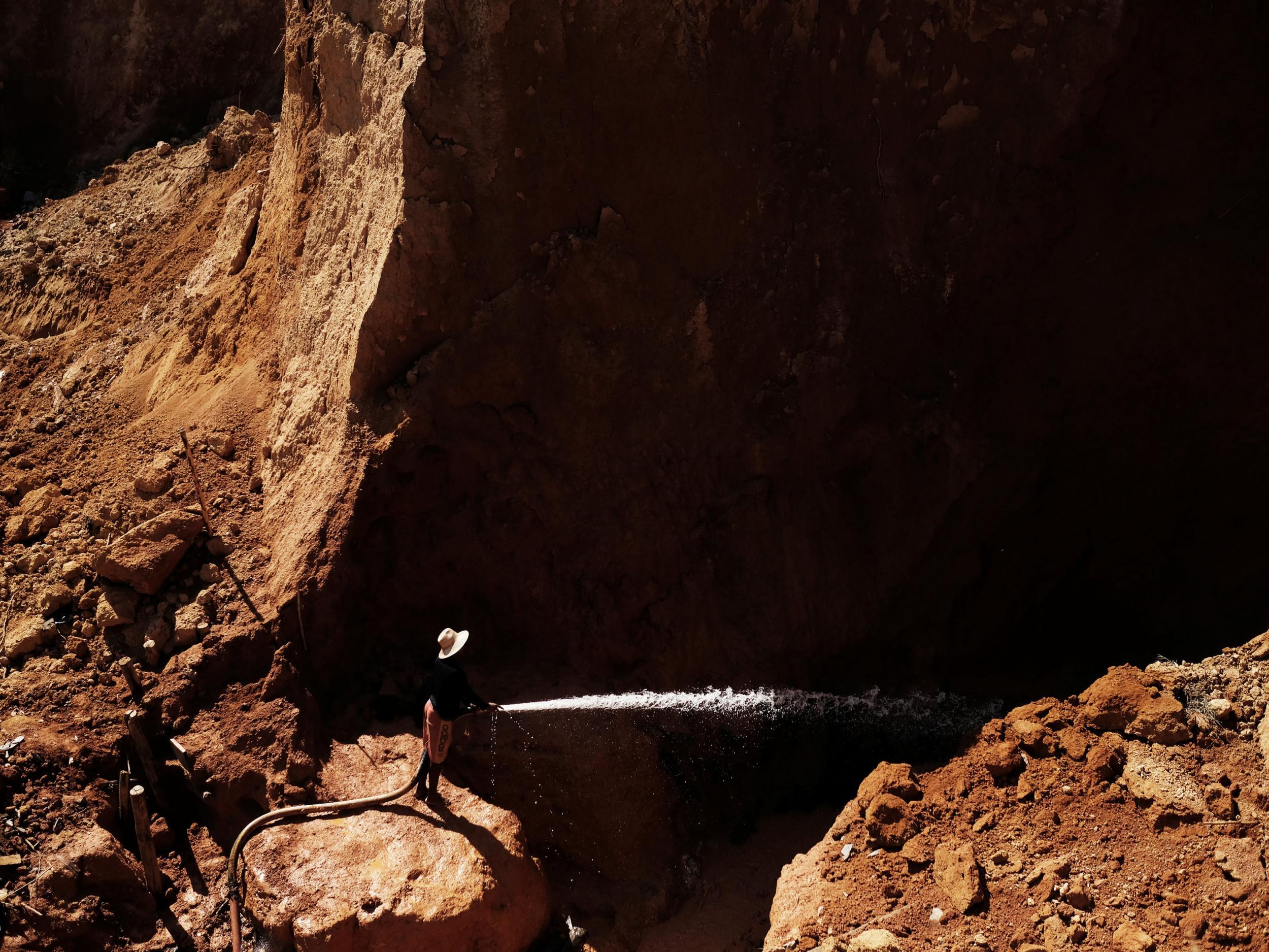 A wildcat gold miner, or garimpeiro, uses high-pressure jets of water to dislodge rock material at a wildcat mine