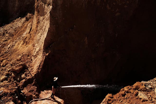 A wildcat gold miner, or garimpeiro, uses high-pressure jets of water to dislodge rock material at a wildcat mine
