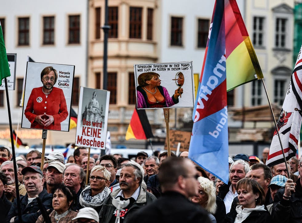 Supporters of the 'Pegida' movement and German right-wing populist party Alternative für Germany (AfD) hold banners at a rally in Dresden