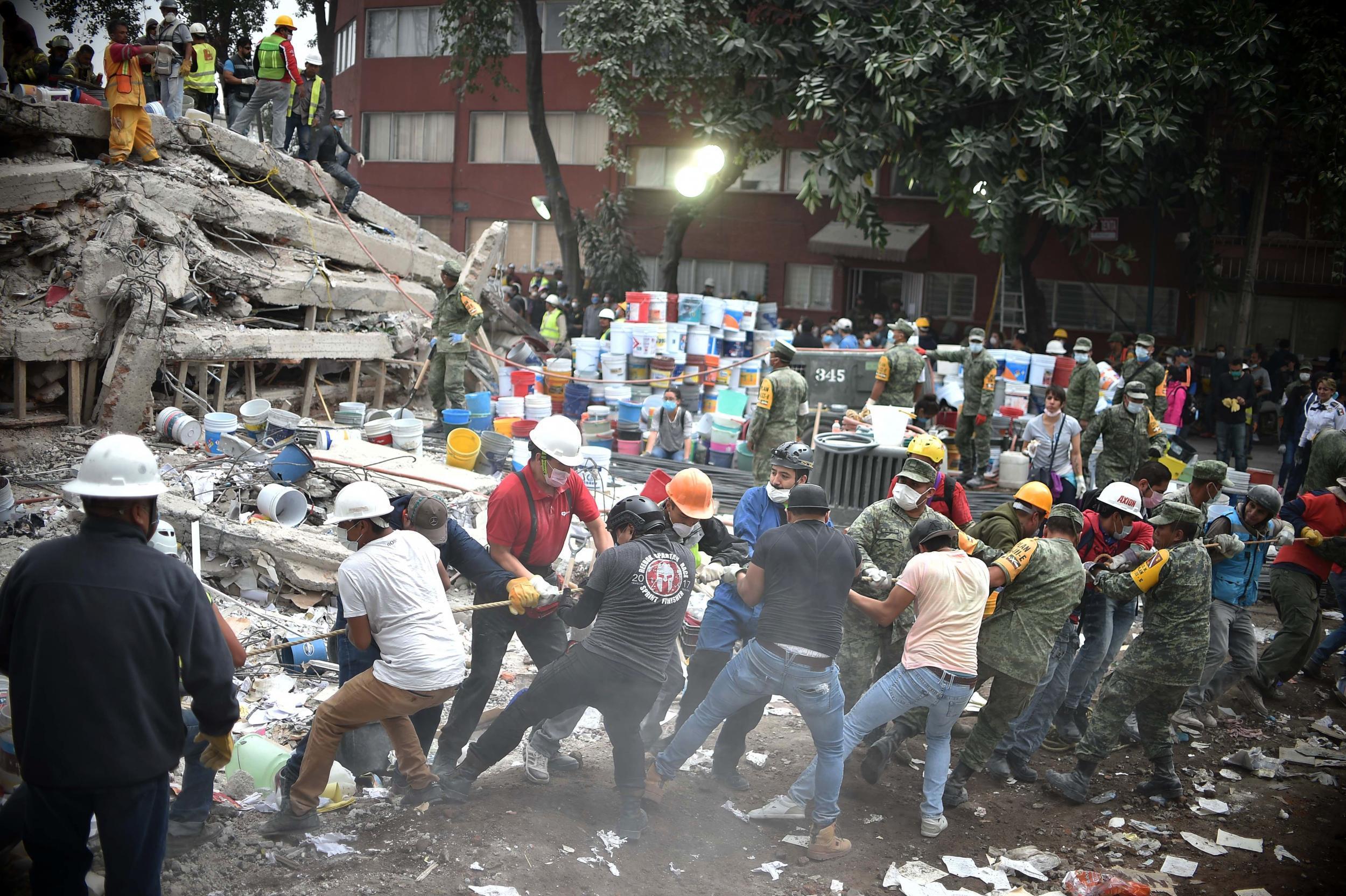 Rescuers, firefighters, policemen, soldiers and volunteers search for survivors in a flattened building in Mexico City