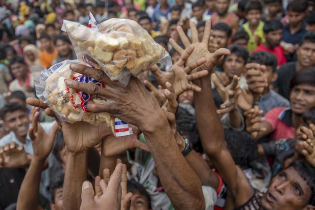 Rohingya Muslims stretch their arms out to receive packets of biscuits thrown at them as handouts