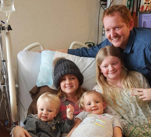 Carrie in the hospital with three of her children and her husband Nick.