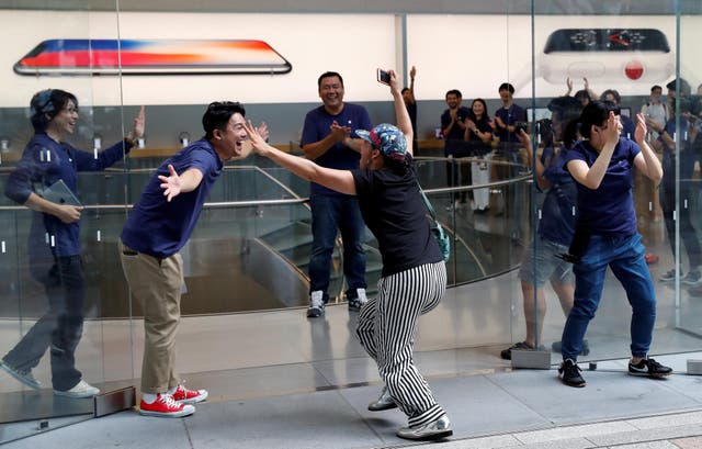 Apple fan Shoko Kimura, who has been waiting in line to purchase new Apple Watch, reacts with Apple Store staff as she enters the Apple Store in Tokyo's Omotesando shopping district, Japan