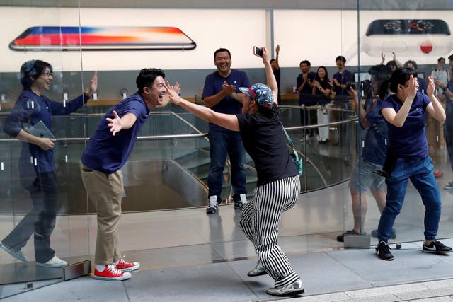Apple fan Shoko Kimura, who has been waiting in line to purchase new Apple Watch, reacts with Apple Store staff as she enters the Apple Store in Tokyo's Omotesando shopping district, Japan